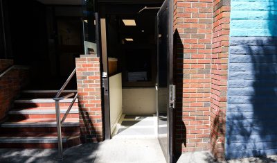 Entrance to a building with brick facade, open door, and stairs.